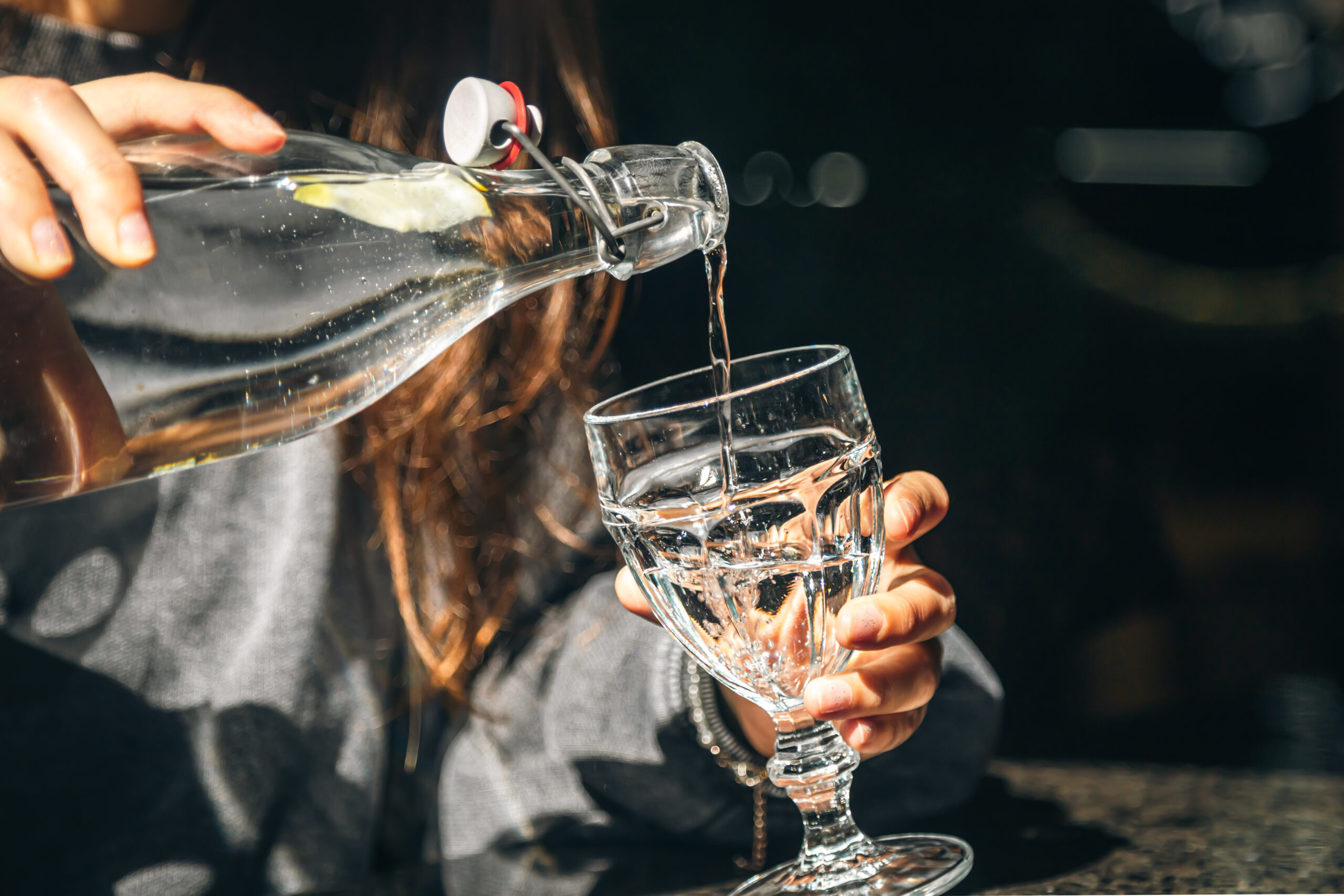 A woman in a cafe pours water into a glass.