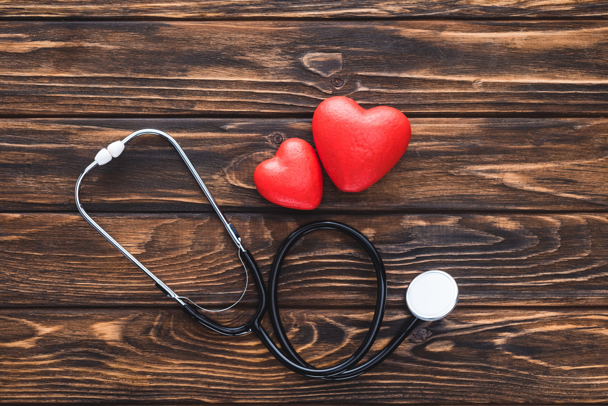 top view of stethoscope and red hearts symbol on wooden table