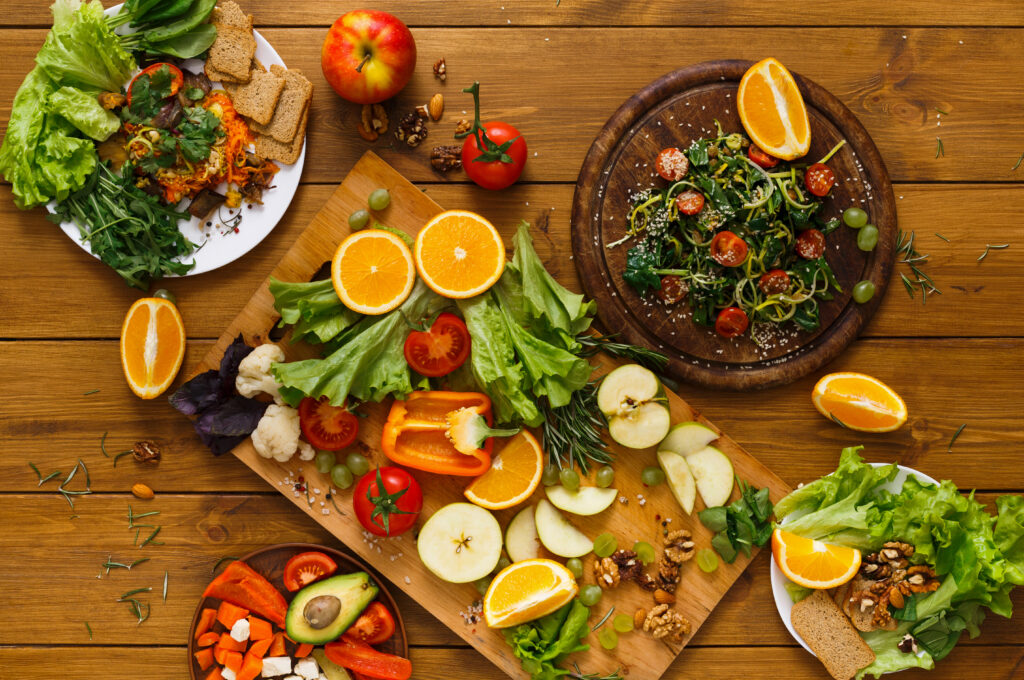 Wooden table served with cut fruits and vegetables. Clean eating foods.