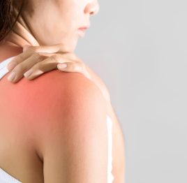 woman holding hand on skin around right shoulder joint with inflammation color